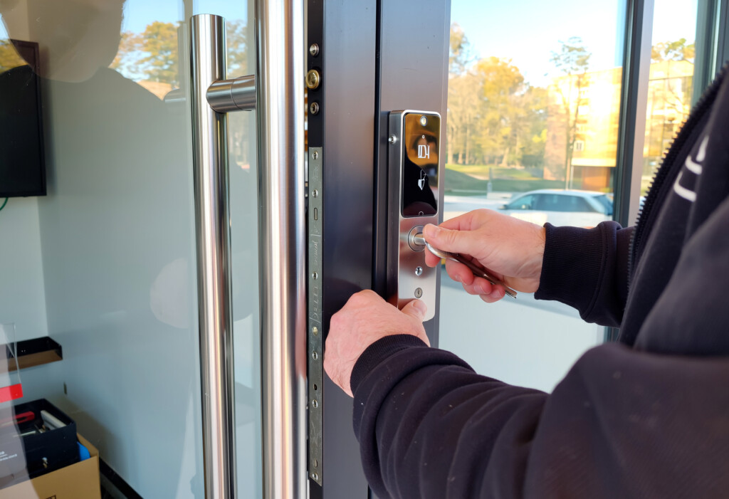 Locksmith installing a commercial door lock at a Charlotte office building